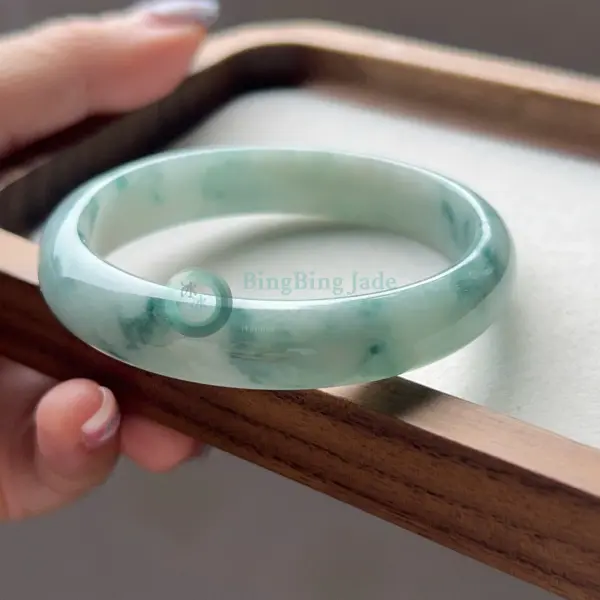 Floating Blossom Oval Jadeite Bangle — Soft Jade Green with Scattered Emerald Wisps
